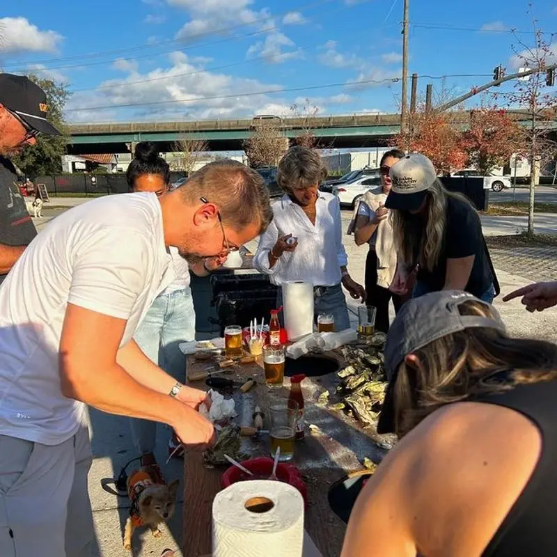 An oyster roast outside the brewery, with guests shucking oysters over a table of beers