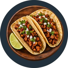Two soft shell tacos filled with seasoned ground beef, chopped onion and cilantro, with a lime wedge